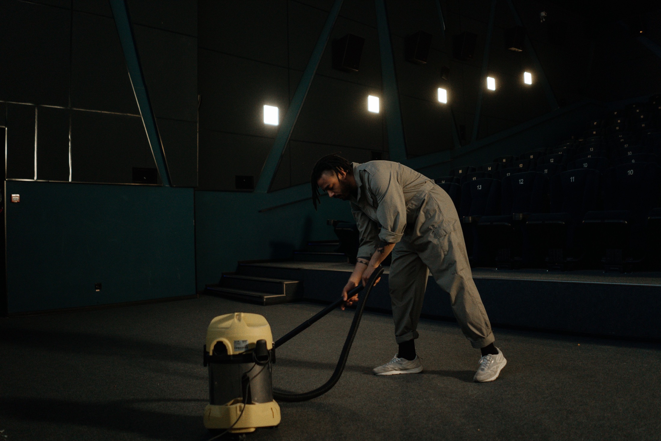 A worker vacuuming a commercial auditorium